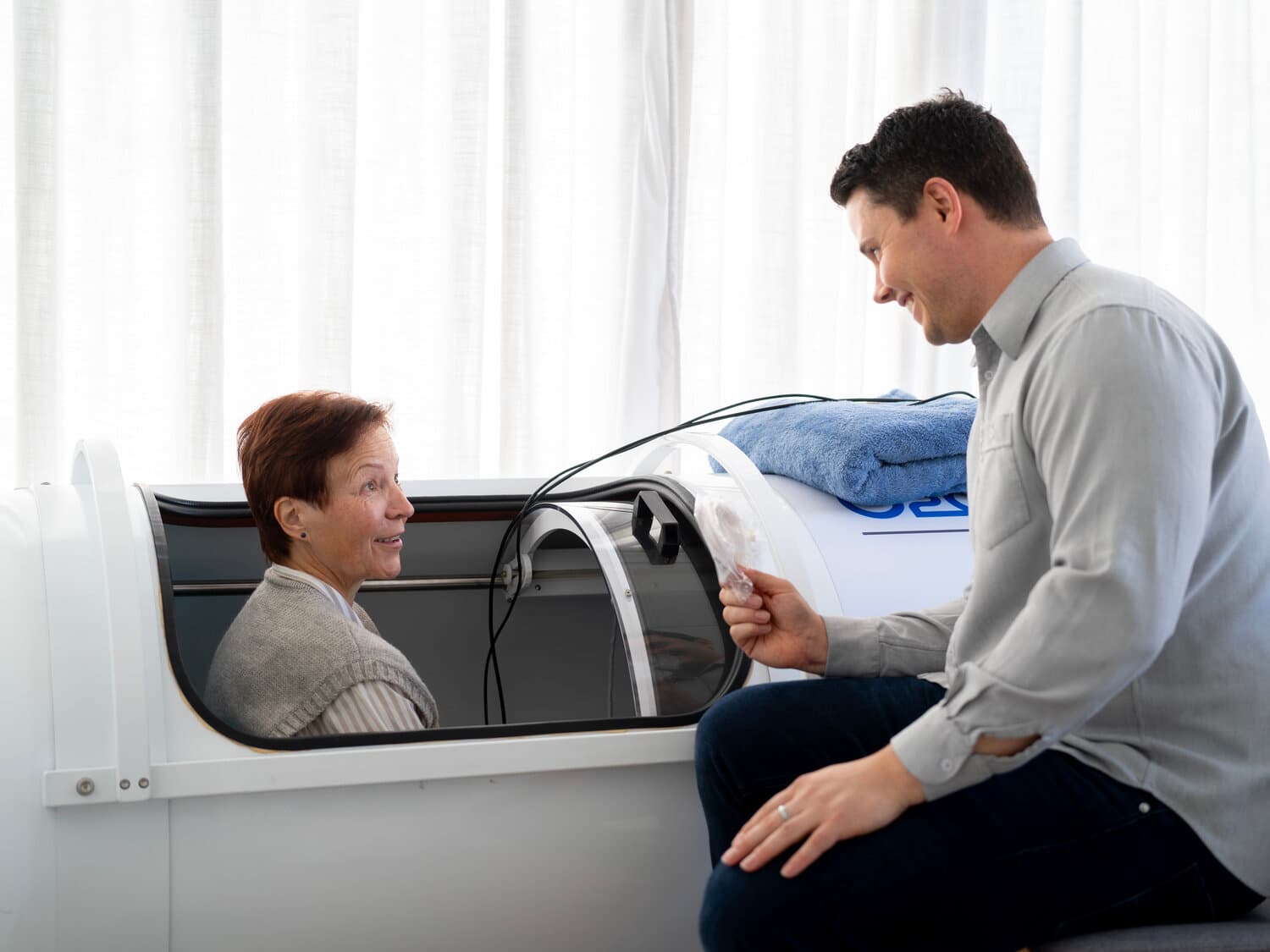Callum providing personal care and support in the hyperbaric chamber Callum sitting beside a patient in the hyperbaric chamber, providing personal care and support