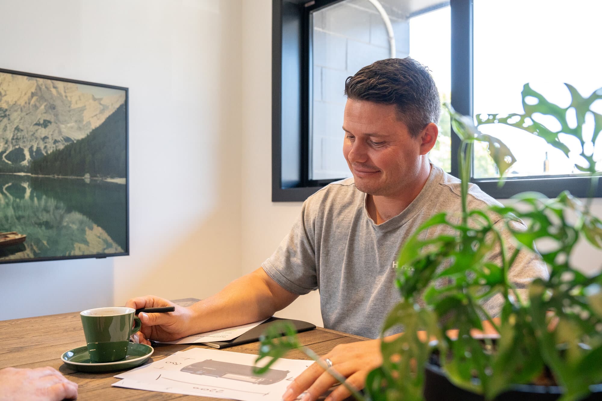 Callum at his desk with coffee, looking warm and approachable